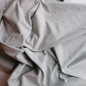 Lichtgrijze ribfluweel stof gedrapeerd