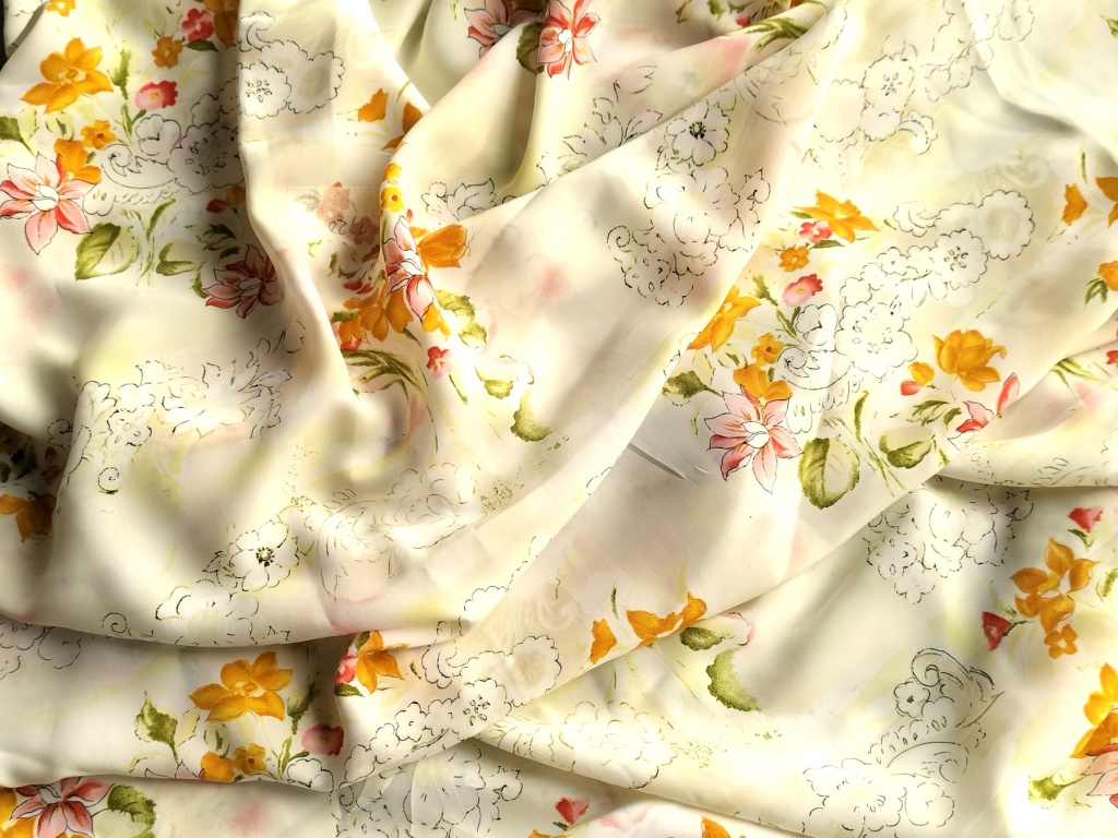Gebloemde viscose stof licht geel met oranje en roze bloemenprint, gedrapeerd