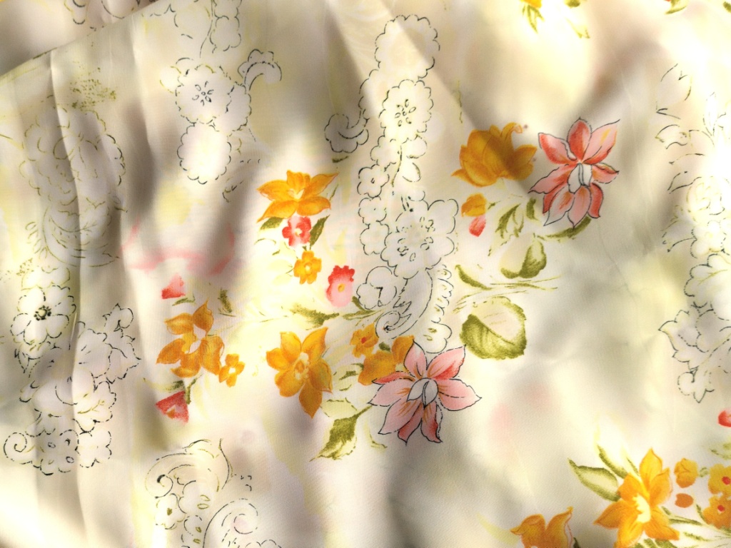 Detail van lichtgele viscose stof met bloemenmotief in oranje en roze tinten