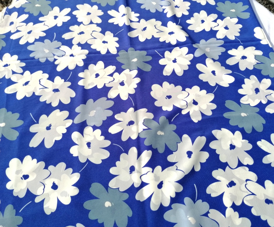 Soepele stof blauw wit gebloemd plat uitgelegd, bloemprint en kleurcontrast duidelijk zichtbaar