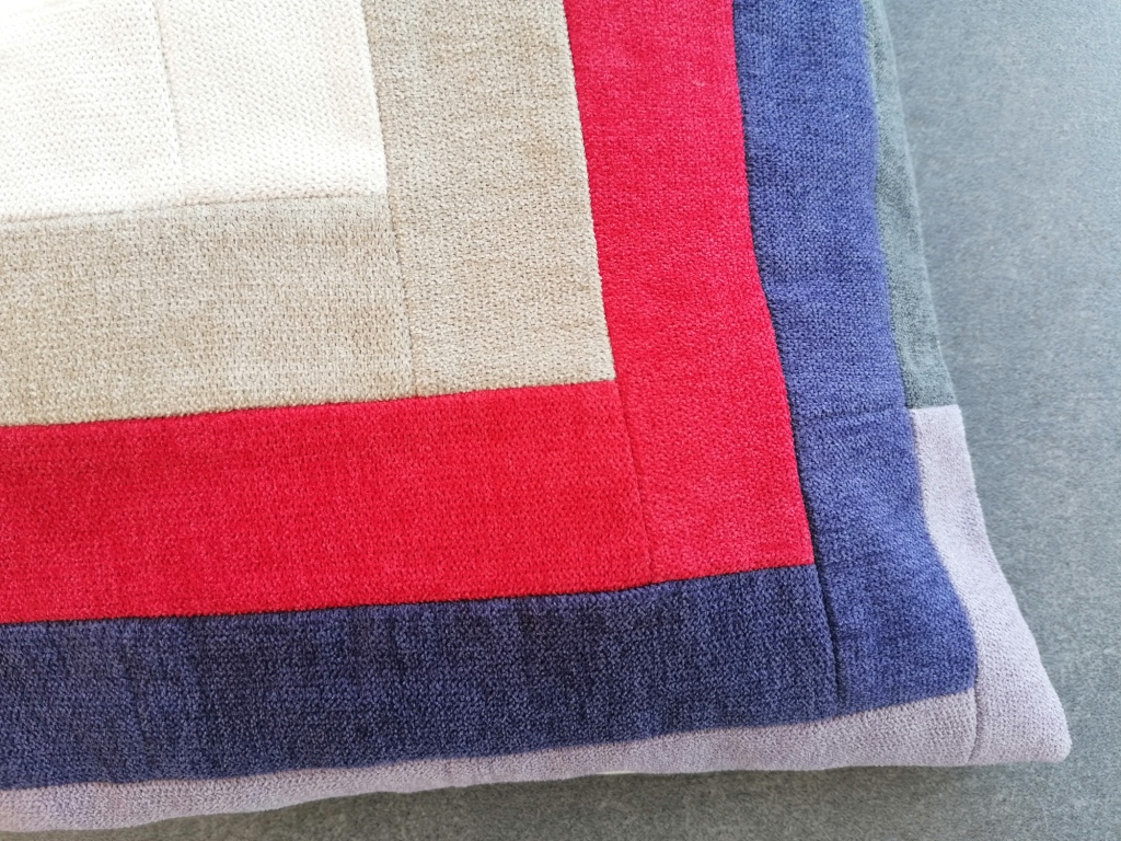 Hoekdetail van fluwelen patchwork kussenhoes met grafisch lijnenspel